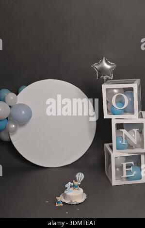 photo verticale du gâteau d'anniversaire avec la figure de l'ours tenant le ballon. gâteau est décoré avec le numéro 1, entouré de ballons bleus sur fond blanc. L Banque D'Images