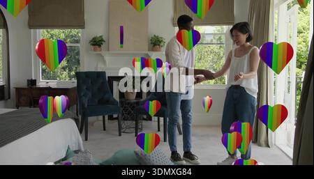 Tenant les mains couple debout dans la chambre, femme en haut blanc, homme en chemise blanche, cœurs arc-en-ciel Banque D'Images