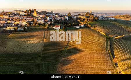 Vue aérienne d'Alice Bel colle au lever du soleil, mettant en valeur le paysage pittoresque du Piémont, Italie. Vignobles vallonnés et charmante architecture baignée Banque D'Images