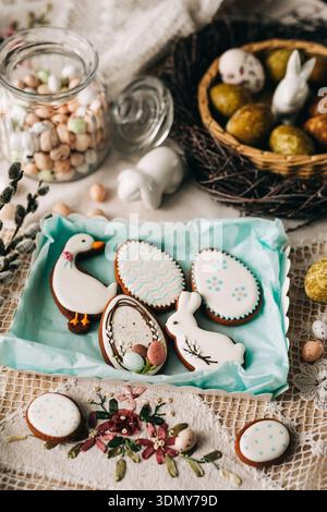 Biscuits de Pâques décoratifs avec des motifs pastel comprenant des œufs, des lapins et des canards, disposés sur une nappe de dentelle, capturant l'essence d'un festi Banque D'Images