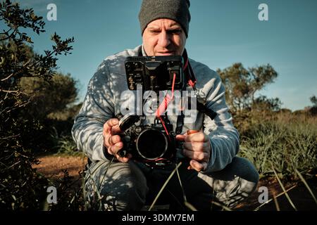 Vidéaste masculin exploitant un équipement de caméra professionnel en extérieur, capturant du contenu Banque D'Images