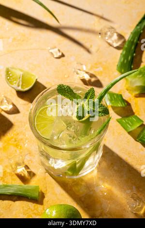 Un cocktail mojito rafraîchissant à l'aloe composé de tranches de citron vert éclatantes et de feuilles de menthe fraîche. Parfait pour l'été, cette délicieuse boisson combine aloès frais et Banque D'Images