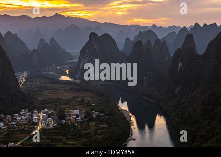 Une vue sereine de la rivière Li serpentant à travers les montagnes karstiques à Yangshuo, Guangxi, au crépuscule. La douce lumière du soir met en valeur les pics calcaires Banque D'Images
