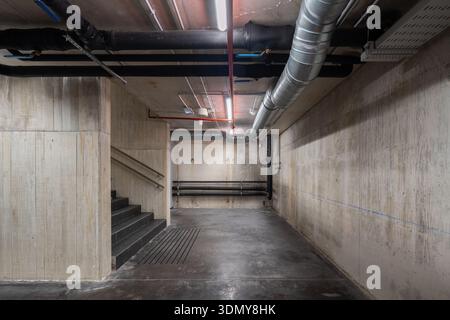 Une vue d’un système de ventilation industriel mis en valeur dans un sous-sol en béton. Les conduits visibles indiquent une infrastructure HVAC complexe nécessaire pour cl Banque D'Images