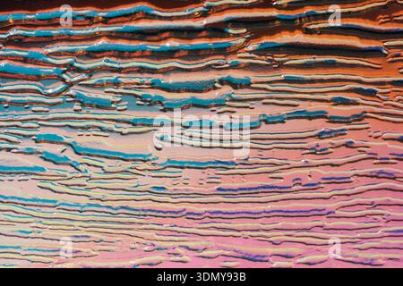 Vue rapprochée d'une surface de verre texturée avec un motif holographique gaufré reflétant les couleurs irisées. Les lignes vibrantes créent un hypnotisme Banque D'Images