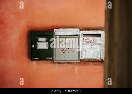 Une série de boîtes aux lettres altérées sont montées sur un mur rustique en stuc. Les boîtes métalliques montrent des signes d'âge et d'usage, évoquant un sentiment de nostalgie et d'urbanisme Banque D'Images
