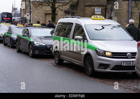 Rangée de taxis verts et jaunes attendant dans un rang sur une rue historique humide dans le centre-ville de Cambridge. Cambridge, Angleterre Banque D'Images