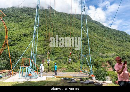 Touristes en tyrolienne dans la forêt tropicale d'Oxapampa Pérou appréciant la balade en canopée au-dessus des montagnes verdoyantes dans un parc d'aventure de la jungle tropicale Banque D'Images
