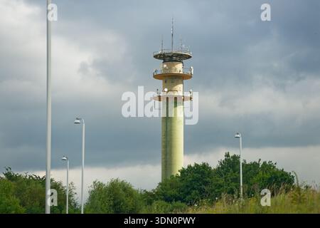 Une haute colonne semblable à une tour s'élève avec trois niveaux d'antenne espacés vers le haut. Chaque niveau a monté des panneaux autour de l'anneau, créant un silho de télécommunications en couches Banque D'Images