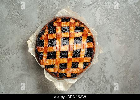 Tarte fraîchement cuite avec un dessus doré et une garniture foncée sur une surface grise Banque D'Images