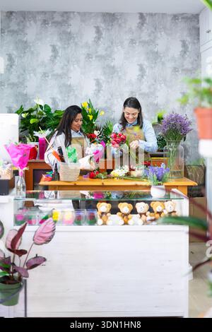 Deux fleuristes préparant des bouquets dans leur magasin de fleurs Banque D'Images