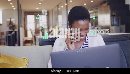 Femme souriante tenant smartphone et regardant ordinateur portable sur canapé gris avec oreiller moutarde et AR HUD Banque D'Images