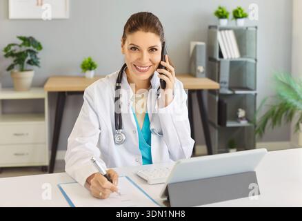Jeune femme thérapeute en manteau consultant patient à distance par appel téléphonique Banque D'Images