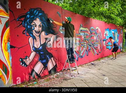 Des artistes de rue peignent en spray une fresque graffiti rouge vive, scène urbaine de Berlin Banque D'Images