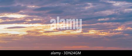 Les nuages s'étendent à travers le ciel au coucher du soleil, montrant diverses nuances d'orange et de violet lorsque la lumière s'estompe. La scène capture les changements dans le ciel du soir Banque D'Images