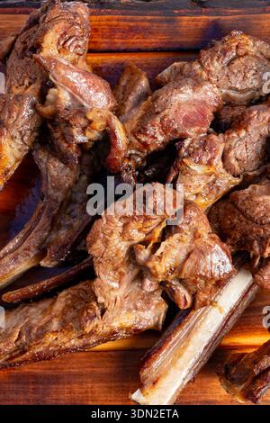 Les gens se rassemblent dans une cour arrière pendant l'été tout en profitant de côtes de barbecue sur une table en bois. Banque D'Images
