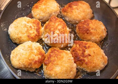 Côtelettes de poulet frites dorées cuisant dans une poêle lors de la préparation des repas maison Banque D'Images