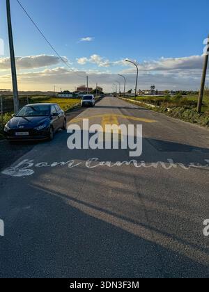 Esposende, Portugal - 24 mars 2025 : marquage routier de Camino de Santiago peint sur asphalte avec flèche jaune et voitures passant à travers la zone rurale Banque D'Images