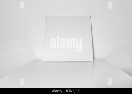 Toile blanche vierge appuyée contre un mur sur une surface de table brillante. maquette pour l'art, la peinture, la conception d'affiches, les présentoirs de produits, ou backgrou minimaliste Banque D'Images