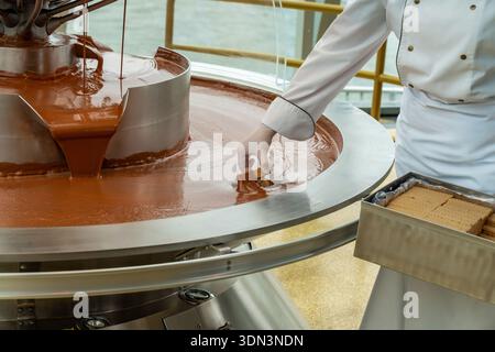 Fusion artisanale de chocolat et contrôle de qualité. Procédure d'usine méticuleuse pour la préparation et l'inspection lisse du chocolat Banque D'Images
