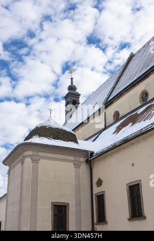 Une église européenne historique avec une grande tour, un clocher sombre et un toit poussiéreux sous un ciel bleu vif. Architecture classique et Winte paisible Banque D'Images
