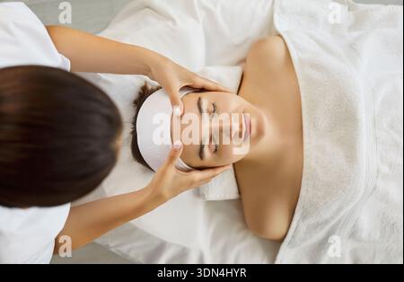 Vue rapprochée ci-dessus d'un masseur féminin faisant un massage facial à la femme Banque D'Images