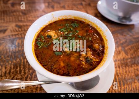 Kharcho, soupe traditionnelle géorgienne traditionnelle avec de la verdure dans l'assiette à proximité. Cuisine géorgienne au restaurant Banque D'Images