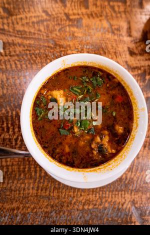 Kharcho, soupe traditionnelle géorgienne traditionnelle avec de la verdure dans l'assiette à proximité. Cuisine géorgienne au restaurant Banque D'Images