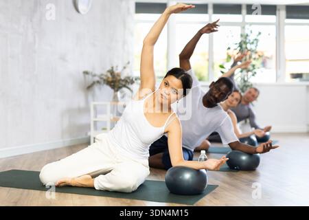 Portrait de jeunes gens heureux portant des vêtements d'activité travaillant à faire des pilates de softball dans un studio de fitness Banque D'Images