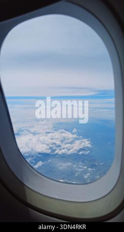 Vue de la fenêtre de l'avion montrant l'aile au-dessus des nuages Banque D'Images