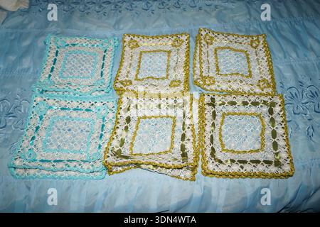 Motifs de dentelle crétoise fabriqués à la main avec des rubans de soie sur tissu bleu. Broderie grecque traditionnelle aux motifs complexes en or turquoise et vert. Banque D'Images