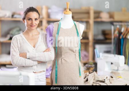 Couturière femme debout à côté du mannequin dans le studio de couture Banque D'Images