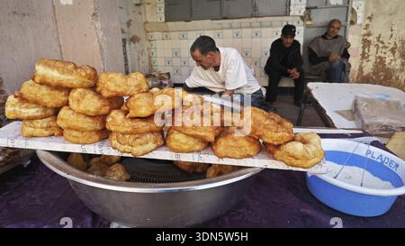 Pâtisseries frites sur un stand de marché entouré de gens dans une rue, sud du Maroc Banque D'Images