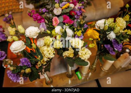 Une variété de fleurs de différentes couleurs et formes sont disposées dans des vases en verre. La composition montre des textures riches et des détails décoratifs. Banque D'Images
