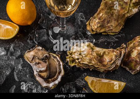 Gros plan sur des huîtres fraîches servies avec citron et vin. Fruits de mer sains, cuisine gastronomique. Banque D'Images
