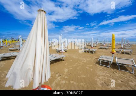 Rangées de chaises de plage vides et parasols sur une plage de sable sous un ciel bleu. Caorle, ville métropolitaine de Venise, Vénétie, Italie Banque D'Images