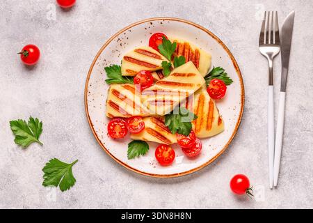 Fromage halloumi grillé servi avec des tomates et du persil. Banque D'Images