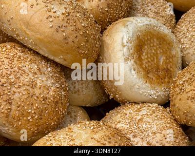 Vue rapprochée de nombreux petits pains aux graines de sésame chauds et croustillants, soulignant leur texture saine et leur arôme invitant, parfaits pour le petit déjeuner ou un HEA Banque D'Images