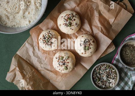 Vue de dessus des petits pains keto Low Carb faits avec ricotta, amande et farine de noix de coco et des œufs surmontés de graines assorties sur une table avec des ingrédients Banque D'Images