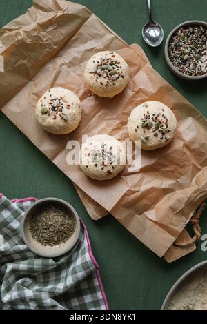 Vue de dessus des petits pains keto Low Carb faits avec ricotta, amande et farine de noix de coco et des œufs surmontés de graines assorties sur une table avec des ingrédients Banque D'Images