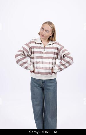 Femme confiante en pull rayé avec les mains sur les hanches Banque D'Images