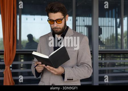 Homme assis sur le banc et lisant un livre noir Banque D'Images