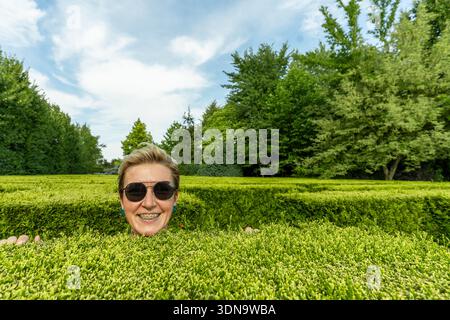 Visiteur souriant tout en explorant un labyrinthe coloré dans un jardin botanique polonais, plein de joie et de bonheur Banque D'Images