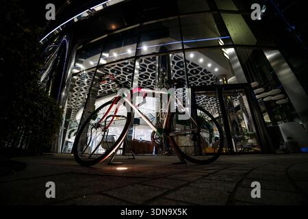 Scène de rue nocturne à Varsovie, Pologne, avec un vélo garé sous les lumières chaudes de la ville. Ambiance urbaine avec des tons de mauvaise humeur et une architecture européenne dans le Banque D'Images