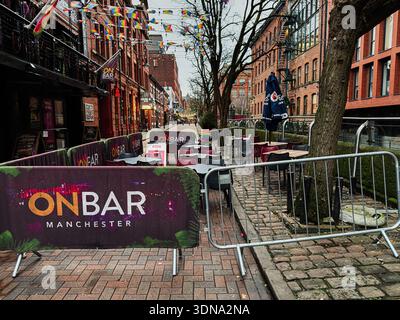 Manchester, Royaume-Uni - 22 janvier 2026 : un coin salon LGBT extérieur animé à côté de bâtiments en briques à Manchester, décoré de drapeaux et de bannières. Banque D'Images