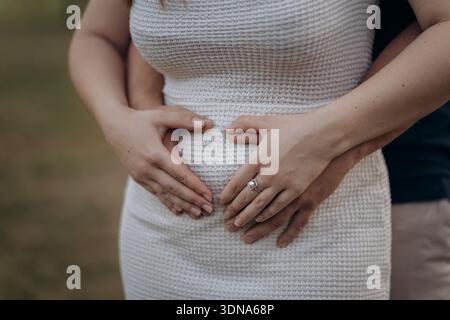 Gros plan de l'attente des mains de couple sur le ventre enceinte, l'amour de maternité et la famille Banque D'Images