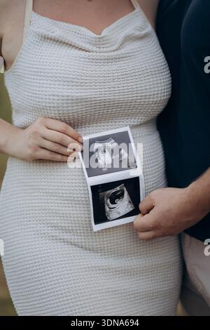 Couple enceinte tenant des photos échographiques sur la bosse de bébé, attendant les parents Banque D'Images