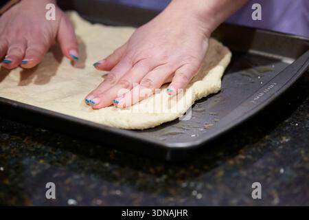Mains étalant la croûte de pizza Banque D'Images