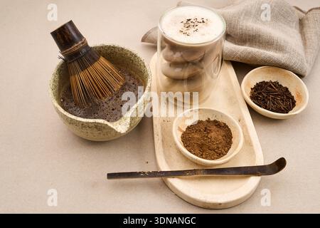 Hojicha latte avec de la mousse et des outils de cérémonie du thé sur un fond clair Banque D'Images