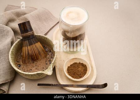 Préparer un hojicha latte avec du thé en poudre, un fouet en bambou et du lait moussé Banque D'Images